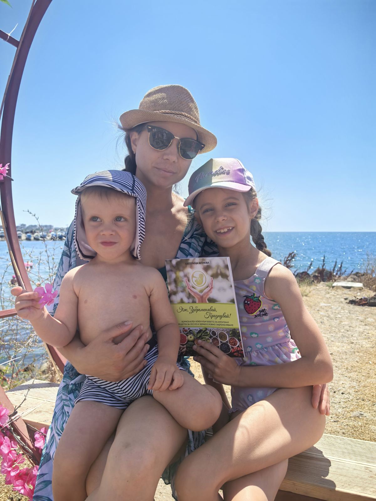 Катерина Илиева с двете си деца и книгата „Яж, Забременявай, Празнувай!“ край морето
